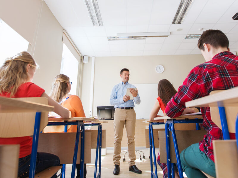 The students are listening to their teacher while he assigns metacognitive journal prompts.